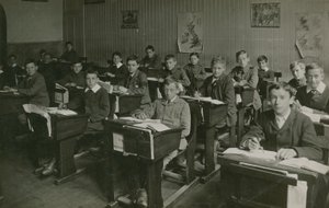Miesoppilaat istuvat pöytänsä takana oppitunnin aikana koulussa tekijältä English Photographer