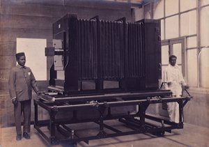 Kaksi intialaista avustajaa seisomassa valtavan kameran vieressä Intian tutkimuslaitoksen valokuvausosastolla, n. 1911 (kuva) tekijältä English Photographer
