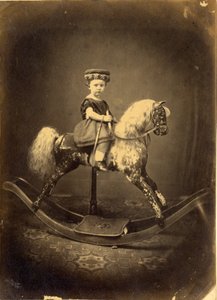 Nuori tyttö istuu keinuhevosen selässä. tekijältä English Photographer