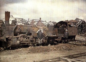 Palanut veturi ja junavaunu pahoin vaurioituneen Vauxrot-tislaamon raunioiden edessä, Cuffies, Aisne, Ranska, 1917 (autokromi)