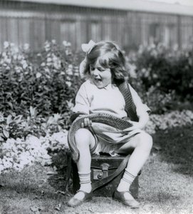 Nuori tyttö Betty pitelee itä-indigo-käärmettä istuessaan nahkaisen arkun päällä, Lontoon eläintarha, 1924 tekijältä Frederick William Bond