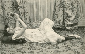 Tyttö, makaa lattialla, pitelee palloa päänsä yläpuolella (m/w kuva) tekijältä French Photographer