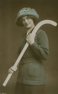 Postikortti nuoresta naisesta, joka kantaa jääkiekkomailaa olkallaan, lähetetty vuonna 1913 tekijältä French Photographer