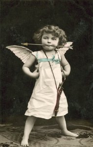 Pieni poika, pukeutunut Cupidoksi, nuoli suussaan tekijältä French Photographer