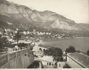 Panoraamanäkymä Montecarloon Monacossa. Kohtaus näyttää erilaisia ohikulkijoita; vasemmalla näemme lähikuvan marmorikaiteesta tekijältä Giacomo Brogi
