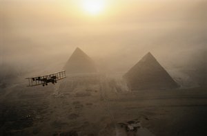 Vintage-lentokone Vimy lentää sumun peittämien pyramidien yläpuolella kultaisen auringonpaisteen aikana....
