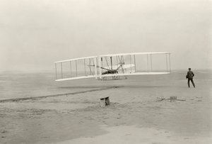 Wright Flyer I tekee ensimmäisen 120 jalan lentonsa 12 sekunnissa Kitty Hawkissa, Pohjois-Carolinassa tekijältä John T. Daniels