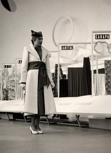 Malli "Lamma" -nimisen couture-talon luomassa päällystakissa. Artikkeli on koottu vyötäröllä leveällä ripsillä, ja se on täydennetty pehmeällä hatulla. Kuva on otettu kankaiden näyttelyyn tarkoitetussa salissa. (s/w-kuva) tekijältä Luis Bogino