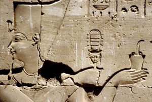 Muinainen Egypti, seinämaalaus/kaiverrus, Faarao Ptolemaios ravistelee systrumia ja tarjoaa suitsukkeita, Horuksen temppeli, Edfu (kuva) tekijältä School Egyptian