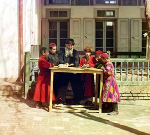 Ryhmä juutalaisia lapsia opettajan kanssa pöydällä talon edessä, Samarkand, Venäjän valtakunta, vuosina 1905-1915