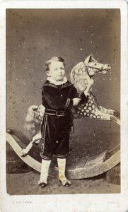 Nuori poika seisoo keinuhevosen vieressä tekijältä Silas Eastham