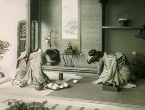 Kaksi japanilaista naista perinteisessä asussa tervehtimässä toisiaan ennen teeseremoniaa, noin 1900 - 1915 (valokuva). tekijältä Teijiro Takagi