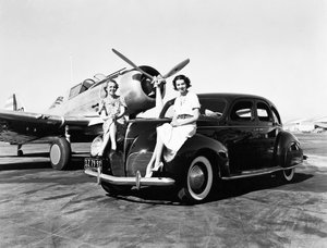 Kalifornia: 1939 Kaksi naista istuvat vuoden 1939 Lincoln Zephyr -sedanin lokasuojissa lentokentällä, ja heidän takanaan on pysäköity yksimoottorinen kone (m/v kuva) tekijältä Unbekannt
