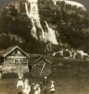 Lapset leikkivät maanviljelijän pellolla, jossa on pengerretty Tvinde-vesiputous, Vossevangen, Norja, c1905. tekijältä Unbekannt