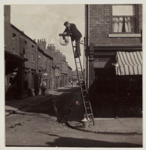 Mies puhdistamassa kaasukatuvaloa, n. 1905 tekijältä Unbekannt