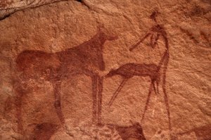 Kalliotaide, esihistoriallinen: Kalliomaalaus lehmästä, vasikasta ja hahmosta (jousimies) koristeellisessa suojissa Uweinatin vuoristossa, Egyptissä. (Ajanjakso 8000-3000 vuotta eKr.). Valokuvaus tekijältä Unbekannt