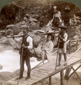 Japanilainen nainen yamakago vuoristotuolissa ylittämässä rankkaa Daiya-jokea lähellä Nikkoa, Japani, tekijältä Underwood and Underwood