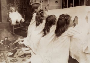 Neljä pientä tyttöä polvistuu sängyn vieressä iltarukousta lausuen. tekijältä Unknown photographer