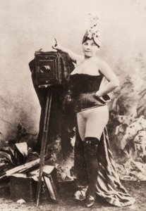 Muotokuva osittain alastomasta naisesta, joka nojaa antiikkiseen kameraan. tekijältä Unknown photographer