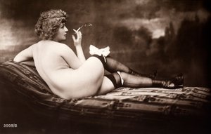 Muotokuva nuoresta naisesta, joka poseeraa alasti, selkä kääntyneenä, savuketta polttaessaan. tekijältä Unknown photographer
