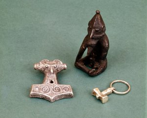 Viikinkijumaluuksien amuletteja: etualalla kaksi pientä hopeavasaraa, jotka symboloivat Thor-jumalaa. Patsas edustaa Freyriä, hedelmällisyyden jumalaa. Tukholman historiallinen museo, Ruotsi.