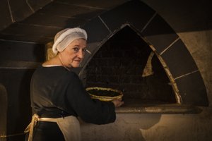Historiallinen esitys: piika laittaa kakun linnan keittiön uuniin tekijältä John Ward Dunsmore