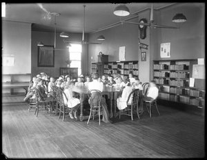 Lapset kuuntelevat naista Queens Borough Public Libraryn tunnistamattoman haaran lukusalissa, n. 1910 (m/v kuva) tekijältä William Davis Hassler