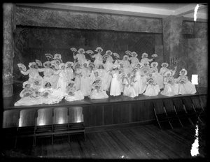 Ryhmä pieniä tyttöjä poseerasi pienellä lavalla faneja pitäen, luultavasti roomalaiskatolinen orpojen turvapaikka, Kingsbridge, Bronx, n. 1911 tekijältä William Davis Hassler