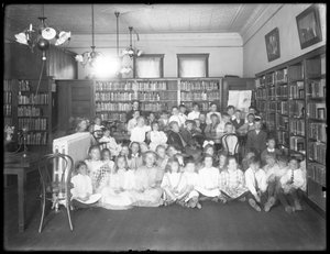 Ryhmäkuva lapsista Queens Borough Public Libraryn tunnistamattoman haaran lukusalissa, n. 1910 tekijältä William Davis Hassler