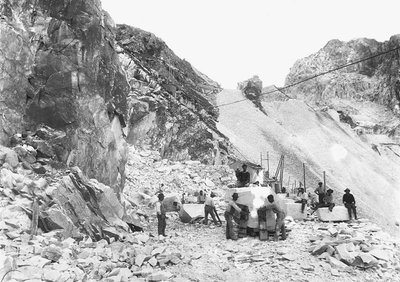 Kaivinkoneet töissä marmorikaivoksella Apuan Alpeilla, Toscanassa. Jotkut heistä istuvat marmorilohkoilla, jotka on jo neliöity. (m/w kuva) tekijältä A. Corsini