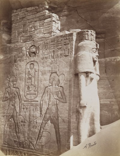 Kuningatar Abu Simbelin temppelissä, näkymä valtaistuimesta ja kuningattaresta istuvan Ramses II:n kolossin alla eteläisen temppelin sisäänkäynnin pohjoispuolella tekijältä Antonio Beato