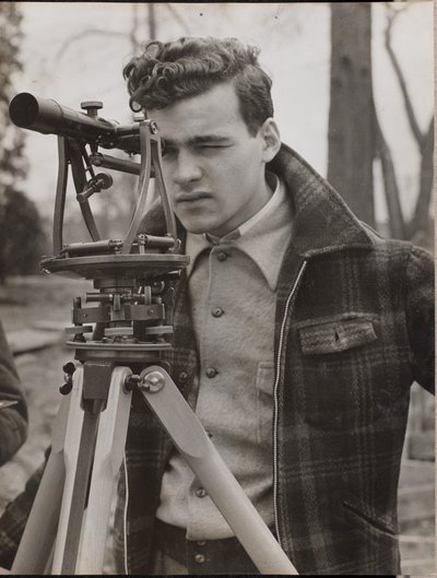 [Nuori mies katselee maanmittarin työkalun läpi] tekijältä Arnold Eagle