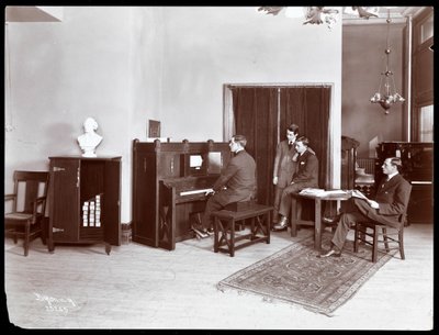 Neljä miestä, yksi soittaa H. Bruman Co. -soitinpianoa, 1907 (hopeagelatiiniprintti) tekijältä Byron Company