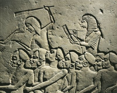 Joukko negroideja vankeja, joita nuijilla aseistetut vartijat ympäröivät, kun kirjuri laatii raporttia. Reliefi Horemhebin haudasta Saqqarassa, yksityiskohtia tekijältä Egyptian 18th Dynasty