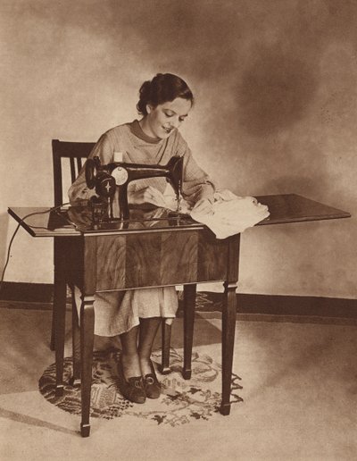 Kotiäiti ompelukoneen ääressä, 1930-luvun puoliväli (s/w-kuva). tekijältä English Photographer