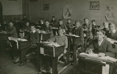 Miesoppilaat istuvat pöytänsä takana oppitunnin aikana koulussa tekijältä English Photographer