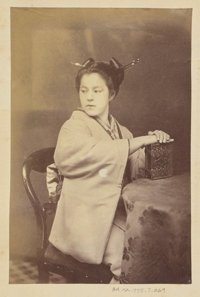 [Istuva japanilainen nainen pitelee pöydän ääressä cartes-de-visite-albumia] tekijältä Felice Beato