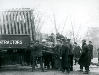 Joukko katsojia seisoo paikalla, kun sarvikuono lastataan kuorma-autosta Lontoon eläintarhassa vuonna 1924. tekijältä Frederick William Bond