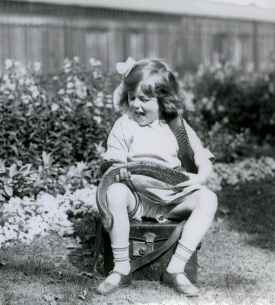 Nuori tyttö Betty pitelee itä-indigo-käärmettä istuessaan nahkaisen arkun päällä, Lontoon eläintarha, 1924 tekijältä Frederick William Bond