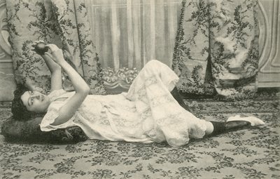 Tyttö, makaa lattialla, pitelee palloa päänsä yläpuolella (m/w kuva) tekijältä French Photographer