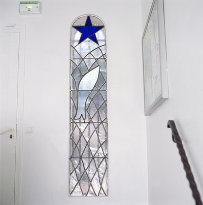 Rukousnauhan kappeliin johtavilta portailta lasimaalaus, joka esittää verkkoon jäänyttä kalaa pelastustähden alla. tekijältä Henri Matisse