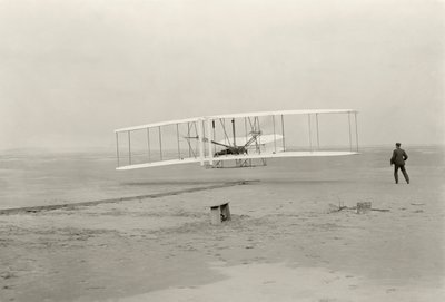 Wright Flyer I tekee ensimmäisen 120 jalan lentonsa 12 sekunnissa Kitty Hawkissa, Pohjois-Carolinassa tekijältä John T. Daniels
