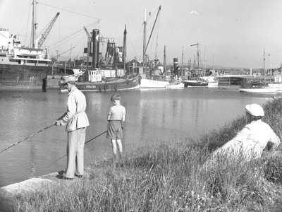 Mies ja poika kalastaa Glasson Dock kuin nainen meri; merimaisema;ted takana katsoo, eri veneet kiinnitetty ylöspäin tekijältä Joseph Hardman