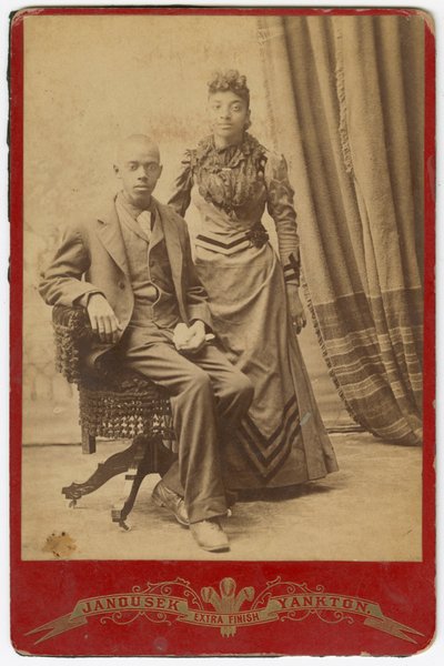Valokuva afroamerikkalaisesta miehestä ja naisesta muodollisissa vaatteissa, 1800-luvun loppu. tekijältä Louis Janousek