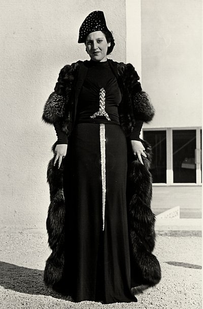 Malli iltapuvussa, jonka on luonut italialainen couture house "Dragoni". Artikkelin fontissa on räikeä, miekan muotoinen paljetekoriste. Hattu ja turkispäällystakki täydentävät kokonaisuuden. (m/w kuva) tekijältä Luis Bogino