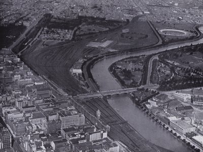 Melbourne: Yarra-joen ja Jolimontin ratapihojen ilmakuva, jossa näkyy pieni osa kaupunkia ja Richmond kaukana (s/w-kuva). tekijältä Photographer Australian