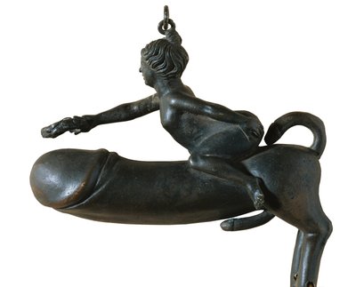 Sasamon Phallus. 1. kr. Eläin, jolla on rinnan, jalkojen ja hännän muotoinen glanssi, jonka päällä on nainen, jolla on laakeriseppele. Amuletti pahaa silmää vastaan. Roomalaista taidetta. Varhainen keisarikunta. Pronssiveistos. ESPANJA. KATALONIA. BARCELON tekijältä Roman Roman