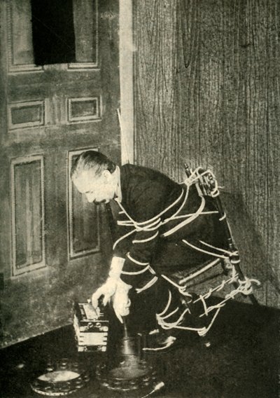 John Nevil Maskelyne esittää henkikaapin illuusion, v. 1910. tekijältä Unbekannt
