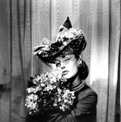 Nainen, jolla on hunnulla varustettu hattu, kädessään kukkakimppu, Pariisi, 1943 tekijältä Unbekannt