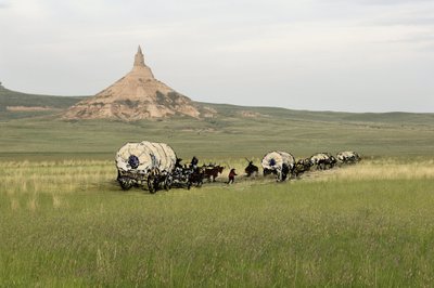 West Conqueten uudisasukkaiden historia: Amerikan pioneerit. Useiden perheiden matkat Yhdysvaltojen tasankojen halki ahkerasti. Diligences ylittää Chimney Rockin Oregon Traililla Nebraskassa. Värikäs kaiverrus yhdistettynä valokuvaan. tekijältä Unbekannter Künstler